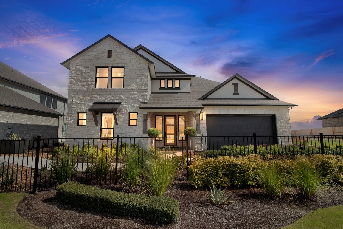 Modern suburban house at sunset with landscaped yard.