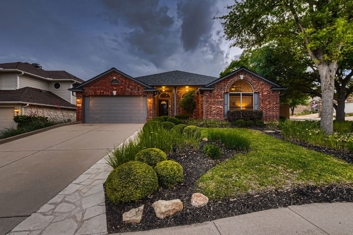Red brick house with green lawn and driveway.