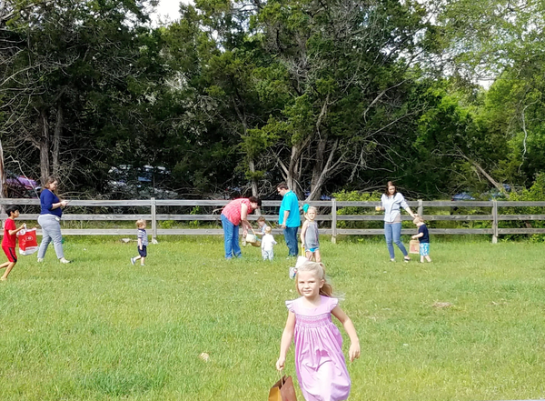 Children playing on a grassy field with adults.