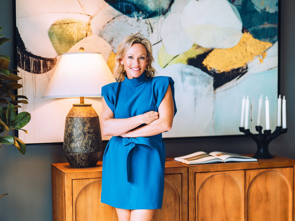 Smiling woman in blue dress by art and furniture.