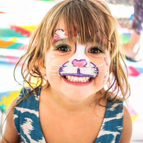 Child with colorful face paint smiling