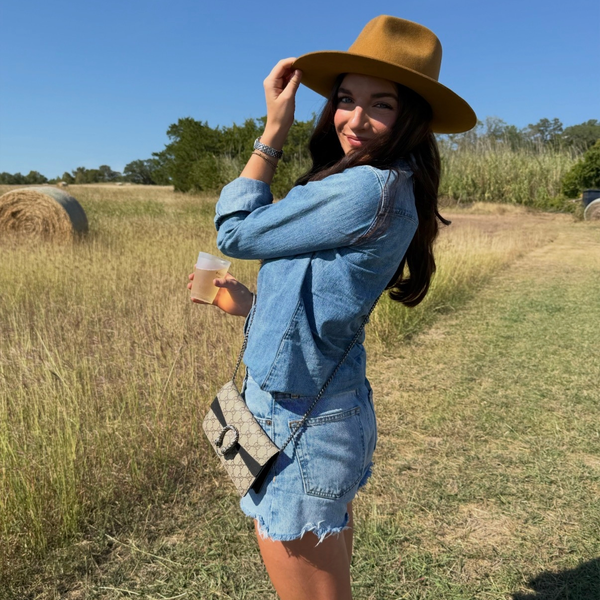 Woman in denim and hat holding a drink