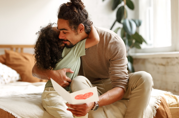 Father hugging child while holding heart card