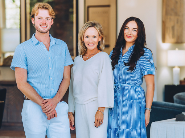 Three people smiling indoors, standing side by side