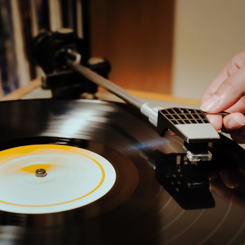 Hand placing needle on spinning vinyl record.