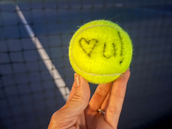 Hand holding tennis ball with heart message