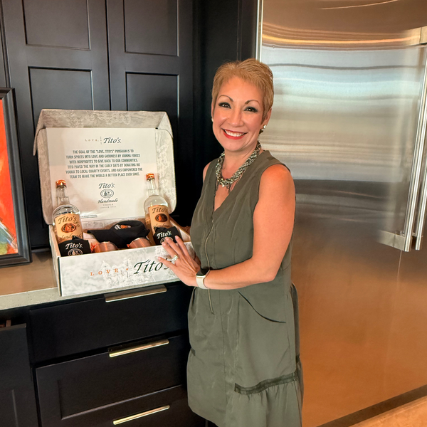 Woman posing with Tito's vodka gift basket in kitchen