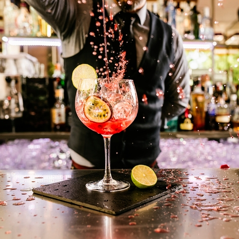 Bartender pours cocktail with lime and passion fruit.