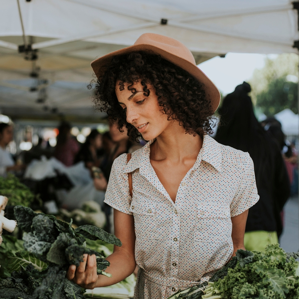 Woman selecting kale at an outdoor farmers market