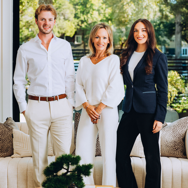 Three professionally dressed people standing in a bright living room