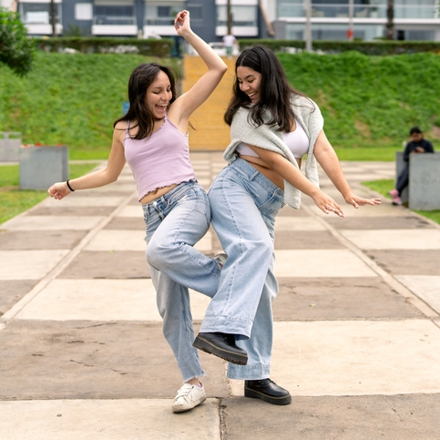 Two women dancing playfully outdoors.