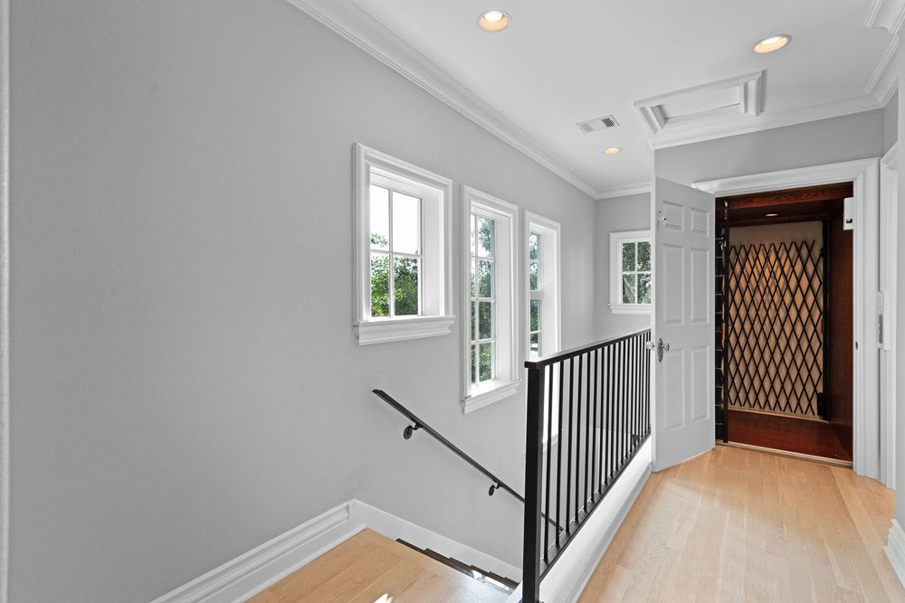 Bright upstairs hallway with elevator and black railing