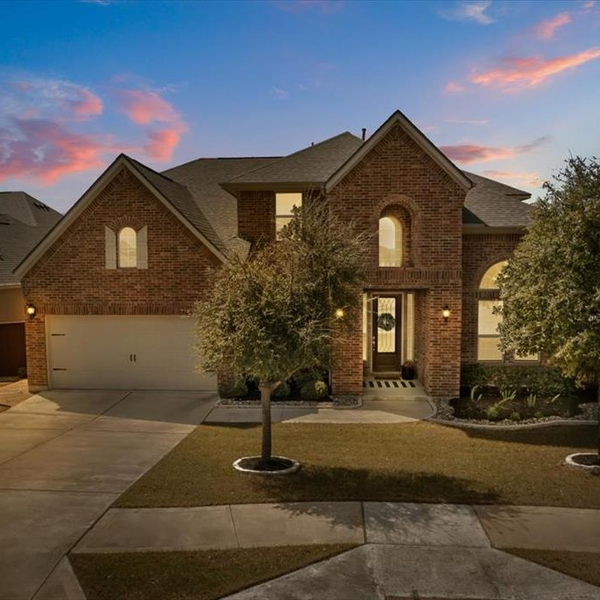 Two-story brick house at dusk with lit windows