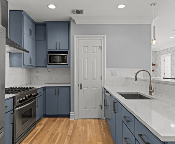 Modern blue kitchen with white countertops and stainless appliances