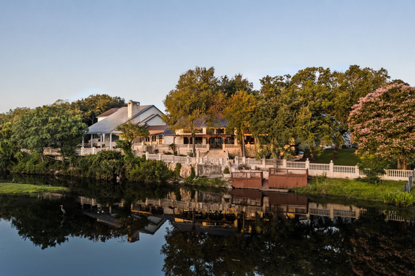 Waterfront house and trees reflected in calm river