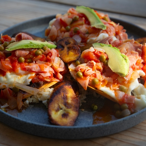 Plantains with avocado, peas, and vegetables on a plate.
