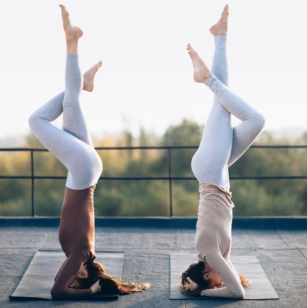 Rope Trix Two women practicing headstands on rooftop yoga mats
