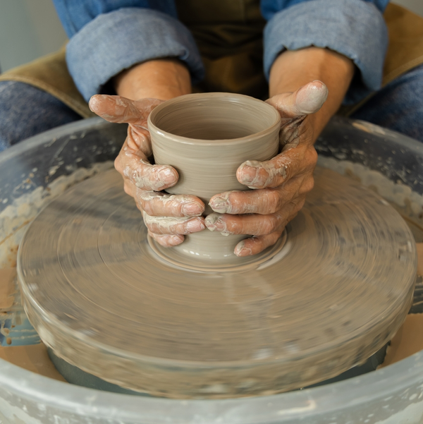 Potter shaping clay bowl on spinning wheel