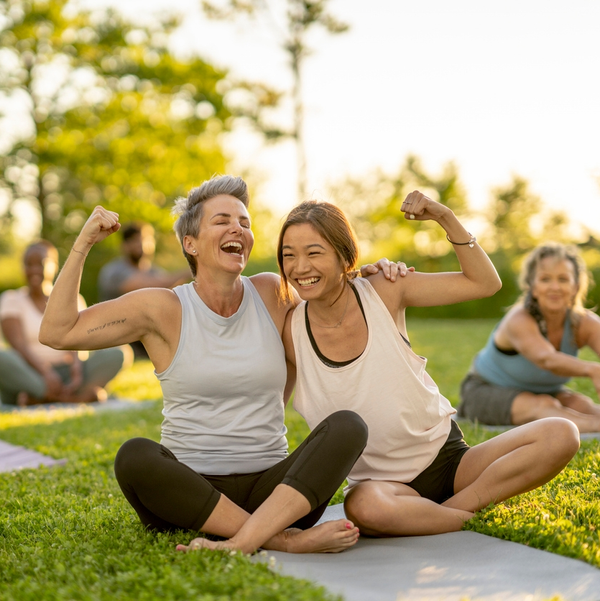 Two women flexing together after outdoor yoga class