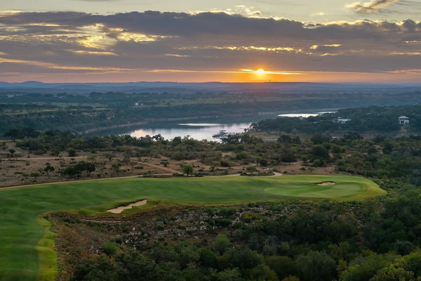 Sunset over a golf course and lake.
