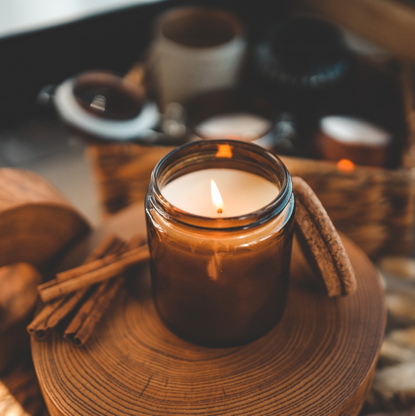 Lit candle in amber jar with cinnamon sticks